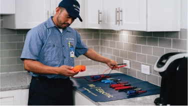 Mr. Electric tech testing outlets in kitchen.