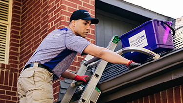 Window Genie associate on ladder cleaning gutters.